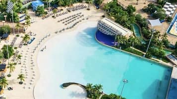 Un resort con una gran piscina, zona de playa y numerosas tumbonas.