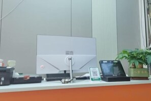 A desk with a computer monitor, a smartphone, a tablet, and a small potted plant. - Sanya New Xiang Theme Tourism Rental (Sanya)