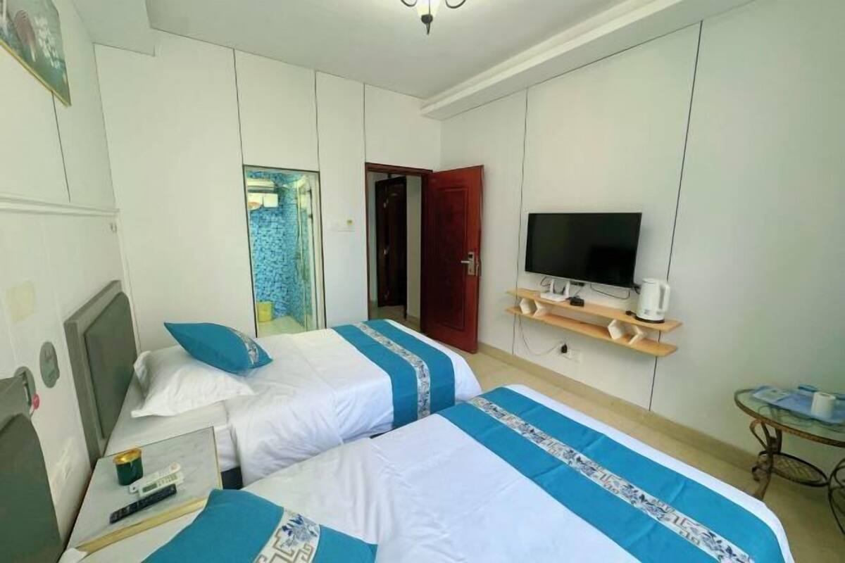 A hotel room with two beds, a TV, a coffee machine, and a small table.