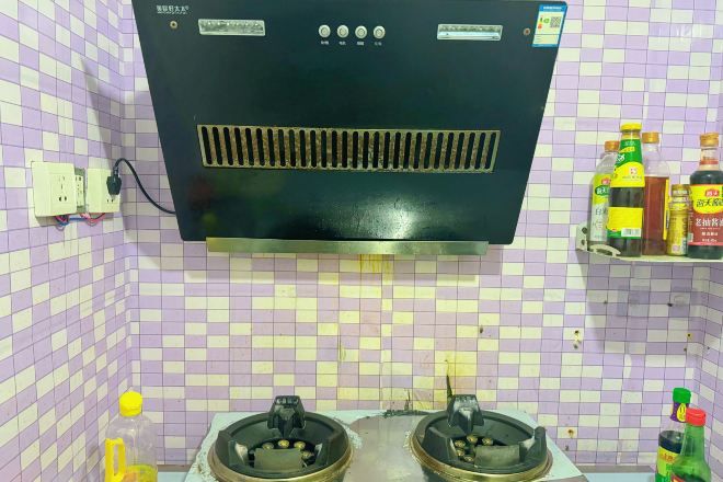 A kitchen with two gas stoves, a black range hood, and a tiled backsplash.