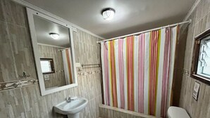 Un baño con lavamanos, inodoro y ducha con cortina a rayas.