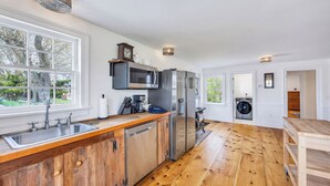 Una cocina moderna con encimera de madera, electrodomésticos de acero inoxidable y ventanas amplias.