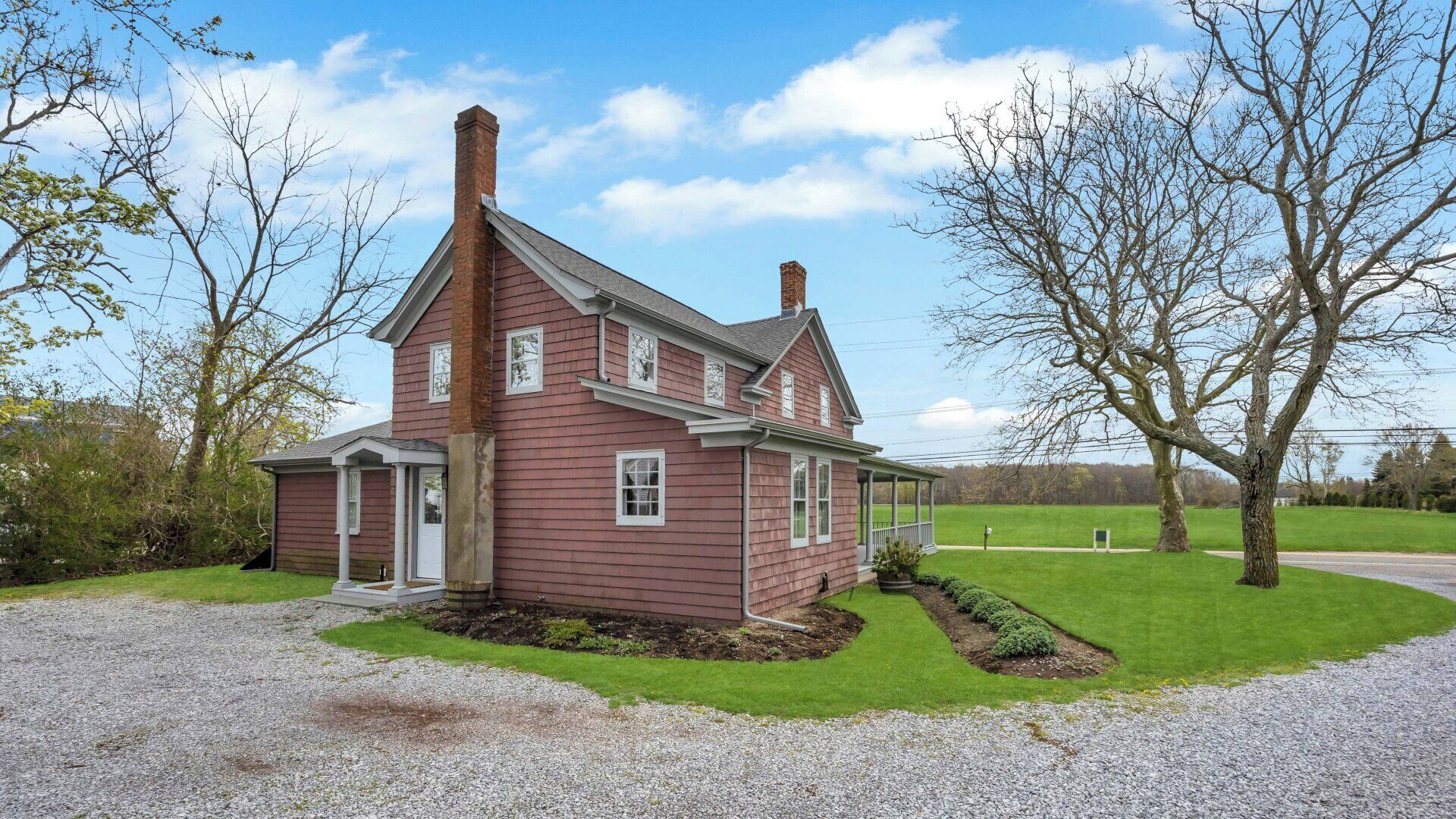 A two-story house with a front porch, a chimney, and a well-maintained lawn.