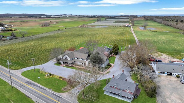 Una propiedad rural con un extenso campo, una casa de campo y una carretera.