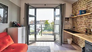 A modern kitchen with a large sliding glass door leading to a balcony, a red sofa, and a brick wall. - Stunning House in Leigh-on-sea (Leigh-on-Sea)