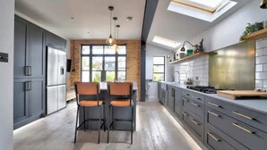 A modern kitchen with grey cabinets, a dining area with two chairs, and a skylight. - Stunning House in Leigh-on-sea (Leigh-on-Sea)