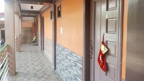 A corridor with a checkered floor, a door with a red cloth hanging, and a wall with a textured pattern. - Idmat Inn (Davao City)