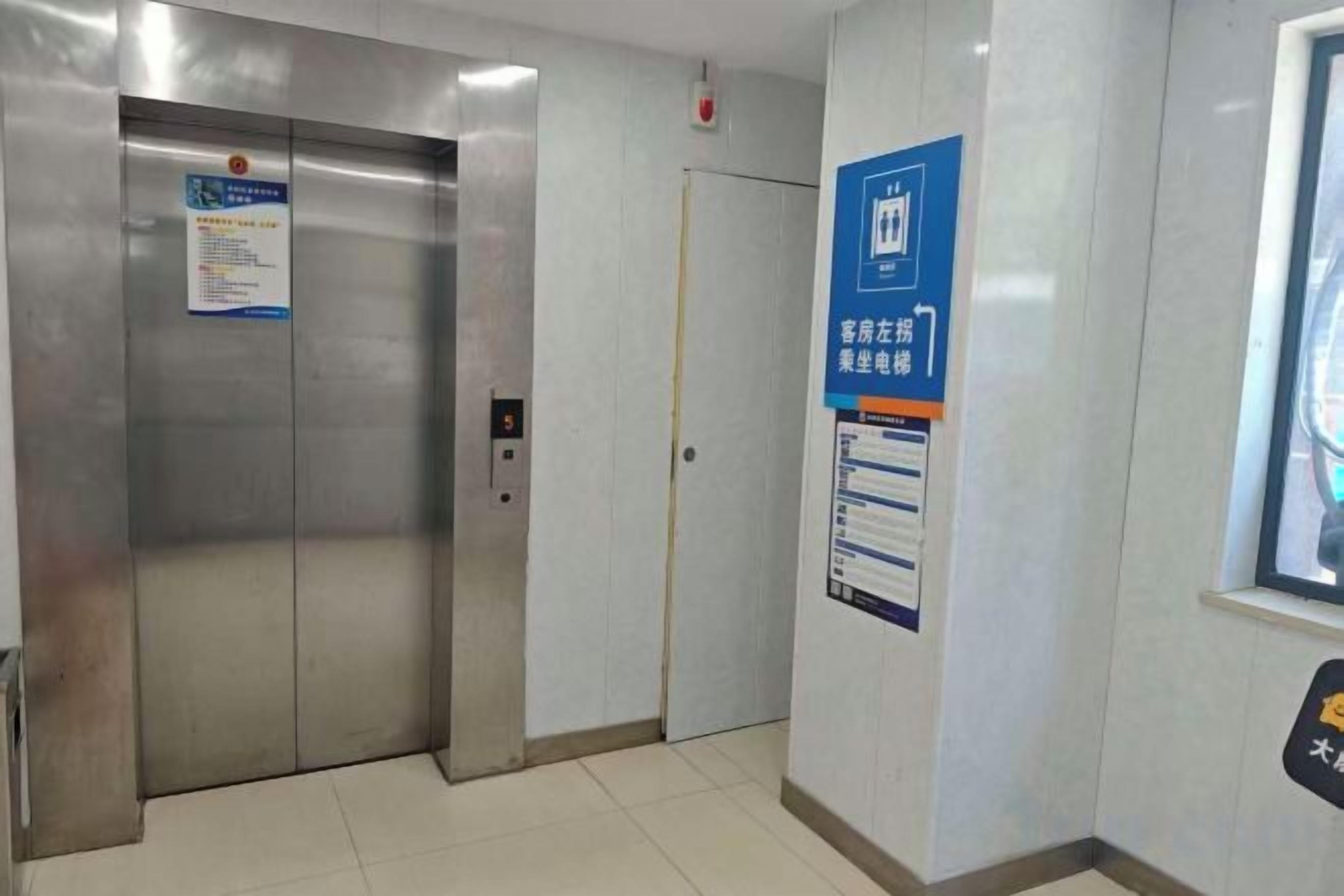 Um elevador com painel de controle e porta, uma placa na parede com texto e uma janela com vista.