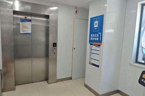 Un ascensor con panel de control y puerta, un letrero en la pared y una ventana con vistas.