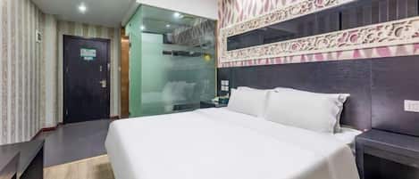 A hotel room with a bed, a desk, a mirror, and a patterned wall.