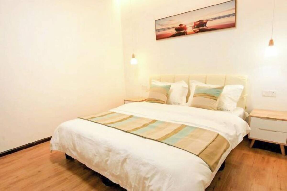 Une chambre à coucher avec un lit, des tables de chevet, une commode et un tableau au mur.