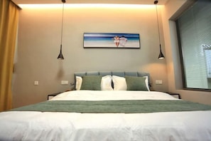 A neatly made bed with a green throw blanket, a headboard with pillows, and a framed picture of a couple on a beach. - Dali Gucheng Nuantu Kezhan (Dali)