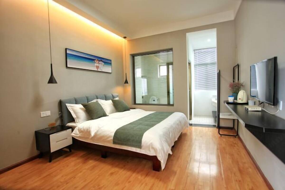Une chambre à coucher comprenant un lit, une table de chevet, une commode et un téléviseur.