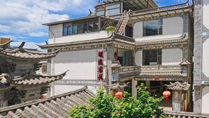 Un edificio tradicional de varios pisos con detalles arquitectónicos ornamentales, incluyendo tejados curvos y azulejos decorativos.