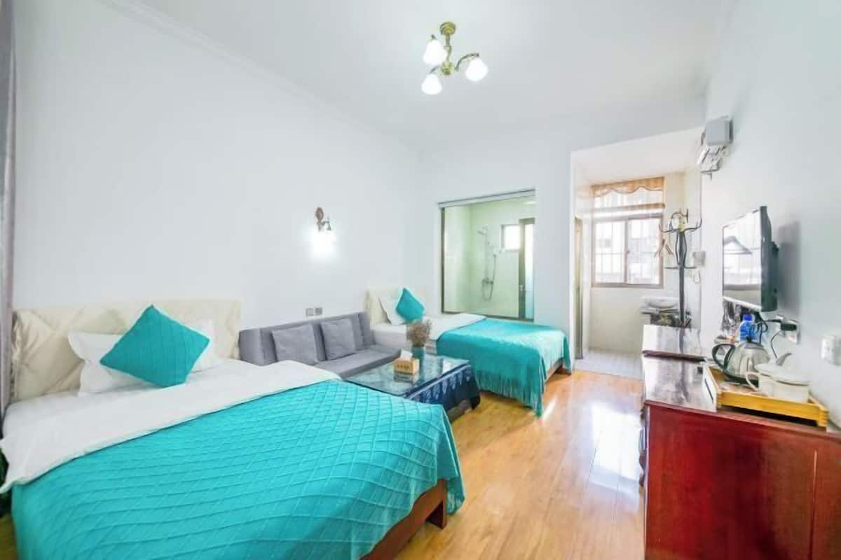 Une chambre d’hôtel avec deux lits, un canapé, une petite table et un téléviseur.