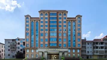 A multi-story hotel with a central entrance, large windows, and a clear sky.