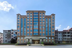 Un hotel de varios pisos con entrada central, ventanas amplias y cielo despejado.