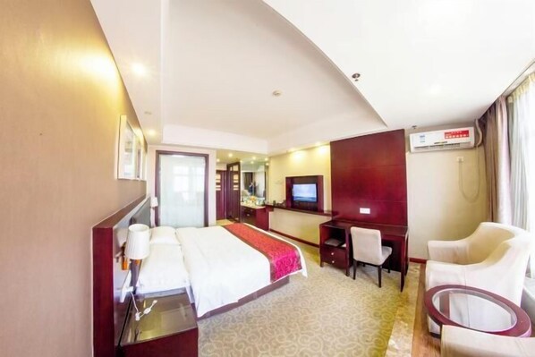 A hotel room with a bed, desk, chair, and a television. - TianchengBusinessHotel (Luxi)