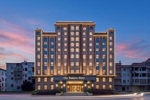 Un hotel de varios pisos con una entrada destacada y un letrero que dice 'City Business Hotel'.