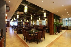 Un restaurante con varias mesas y sillas, una zona de bar y una pantalla de televisión.