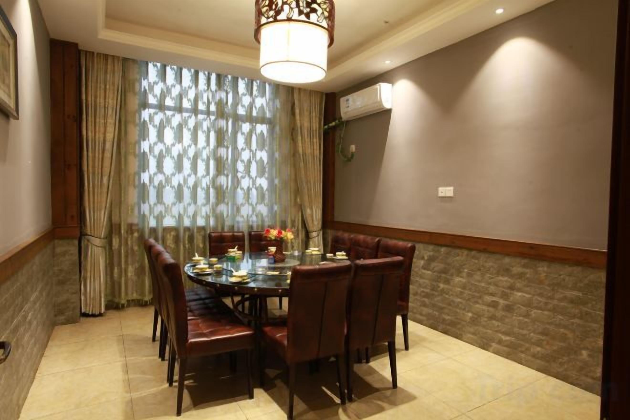 A dining area with a round table, chairs, and a chandelier.