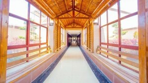 A corridor with wooden beams and large windows, leading to a central area. - TianchengBusinessHotel (Luxi)