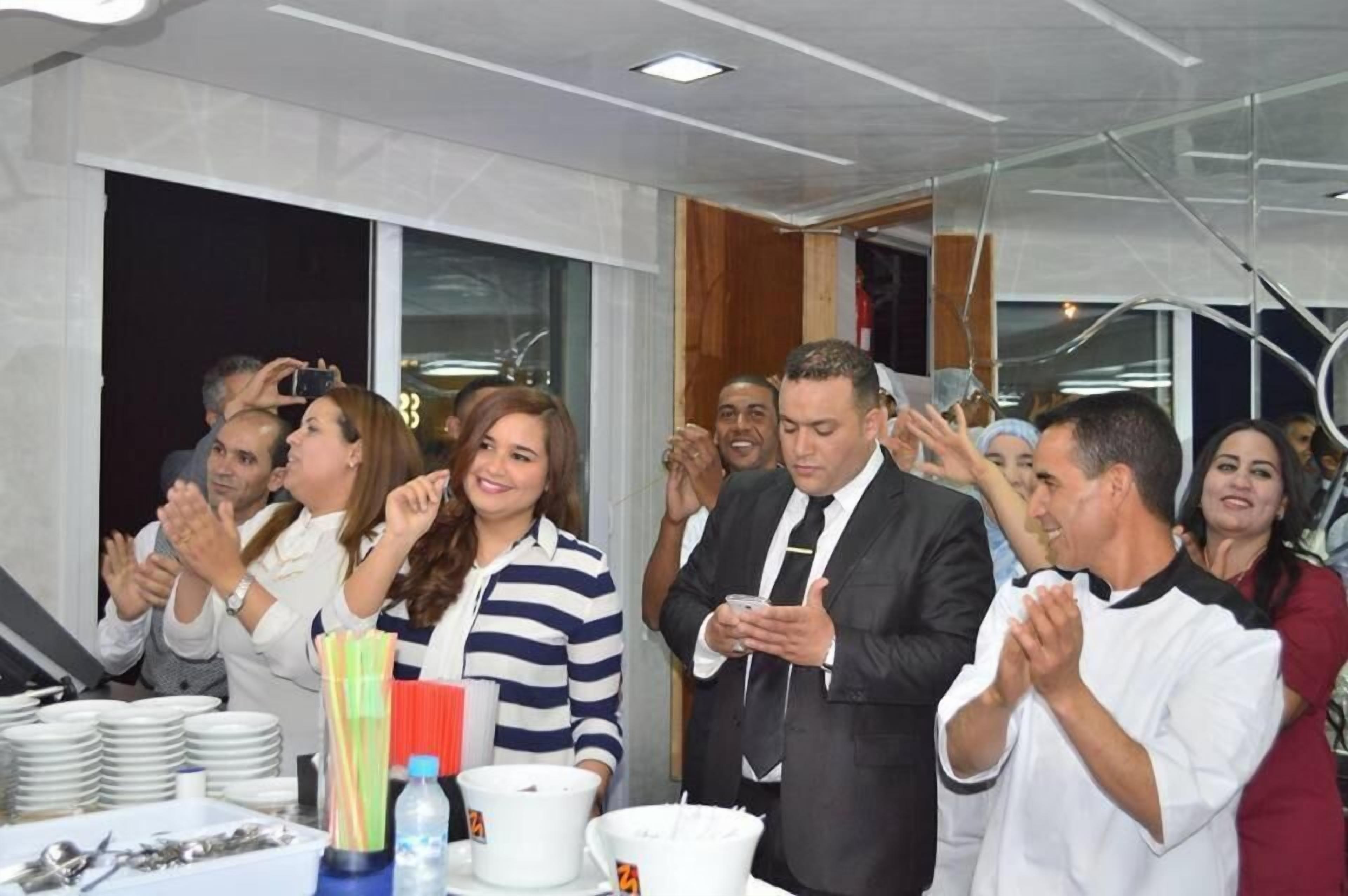 A group of people clapping and celebrating around a table with plates and cups.