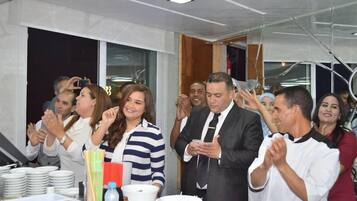 A group of people clapping and celebrating around a table with plates and cups.