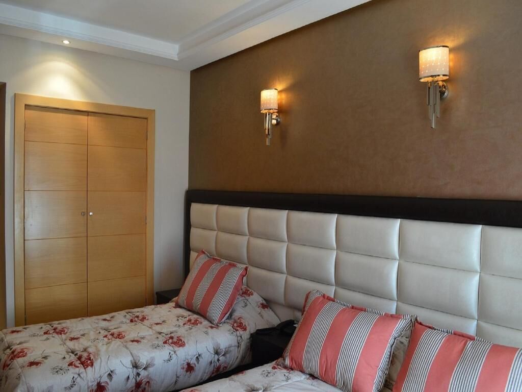 A bedroom with a large bed, two wall-mounted lights, and a wardrobe.