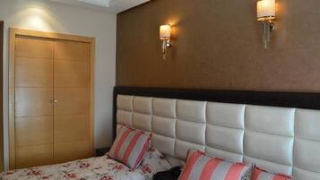 A bedroom with a large bed, two wall-mounted lights, and a wardrobe.