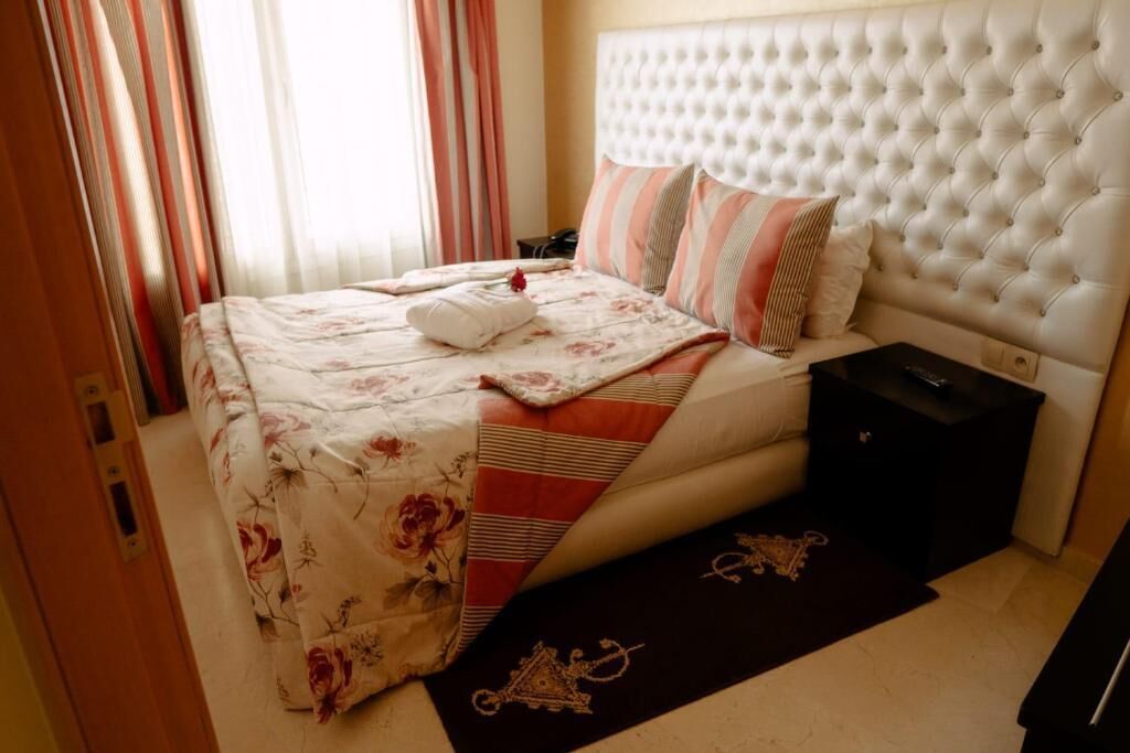 Una cama bien hecha con ropa de cama floral, un edredón a rayas y una almohada decorativa.