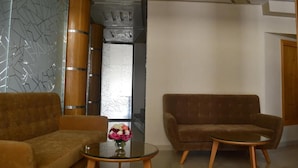 A modern lobby with a sofa, a round table with a vase of flowers, and a wooden cabinet. - Hôtel La Luna (Beni Mellal)