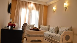 A living room with a sofa, a coffee table, and a TV mounted on the wall. - Hôtel La Luna (Beni Mellal)