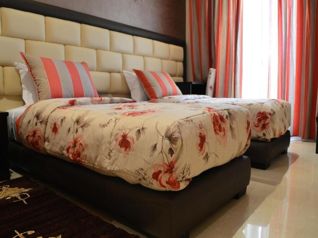 A double bed with floral bedding, a padded headboard, and striped pillows.