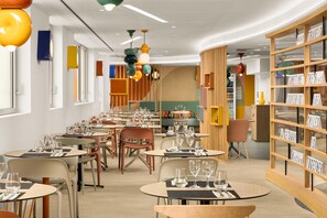 A modern dining area with round tables, chairs, and a variety of hanging pendant lights. - Hampton By Hilton Paris Charles De Gaulle Airport (Roissy-en-France)