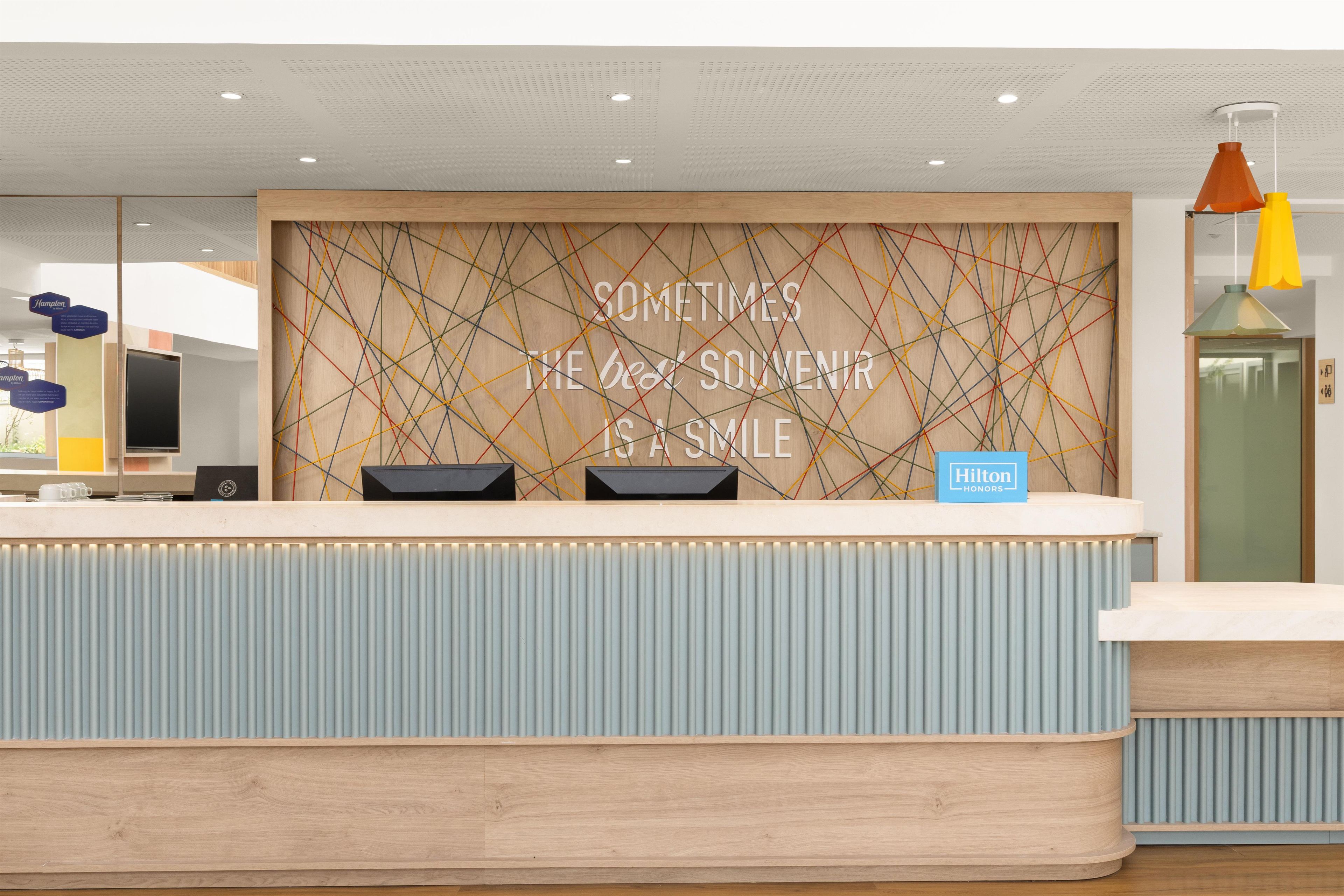 A hotel reception desk with a wooden panel design and a motivational quote.