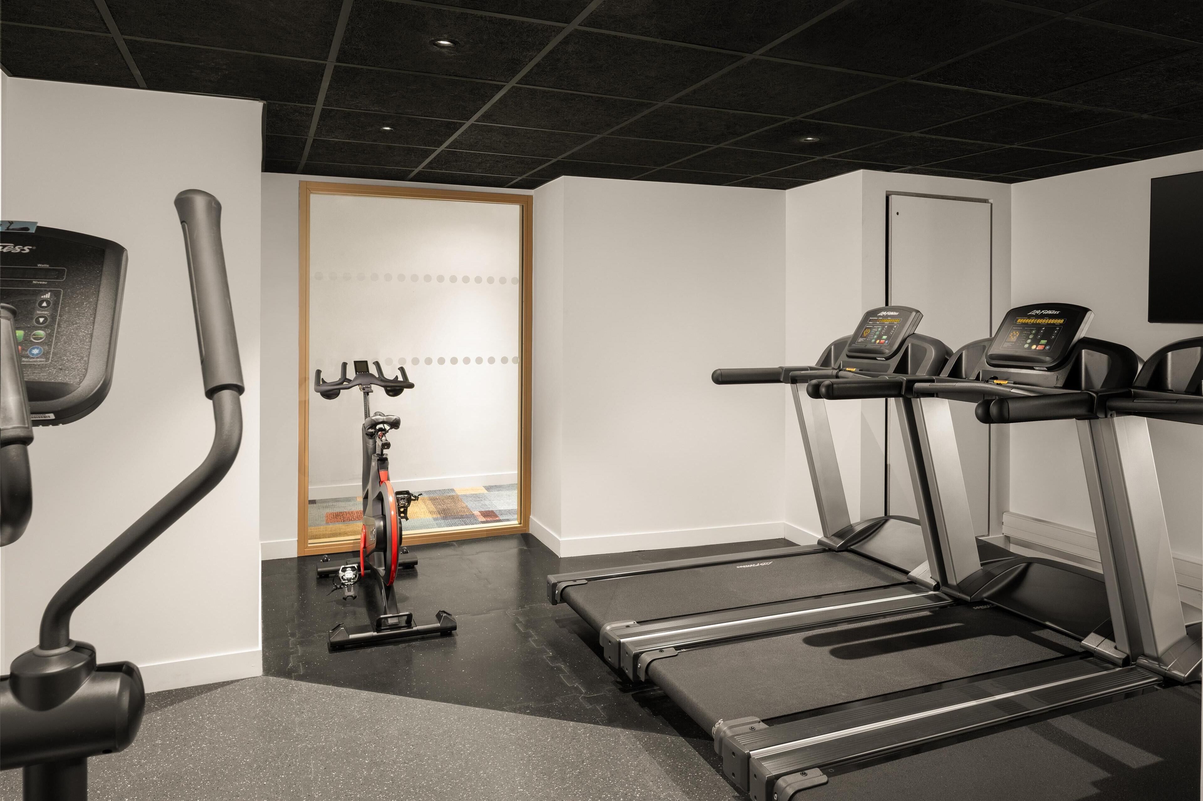 A gym with stationary bikes, treadmills, and a rowing machine.