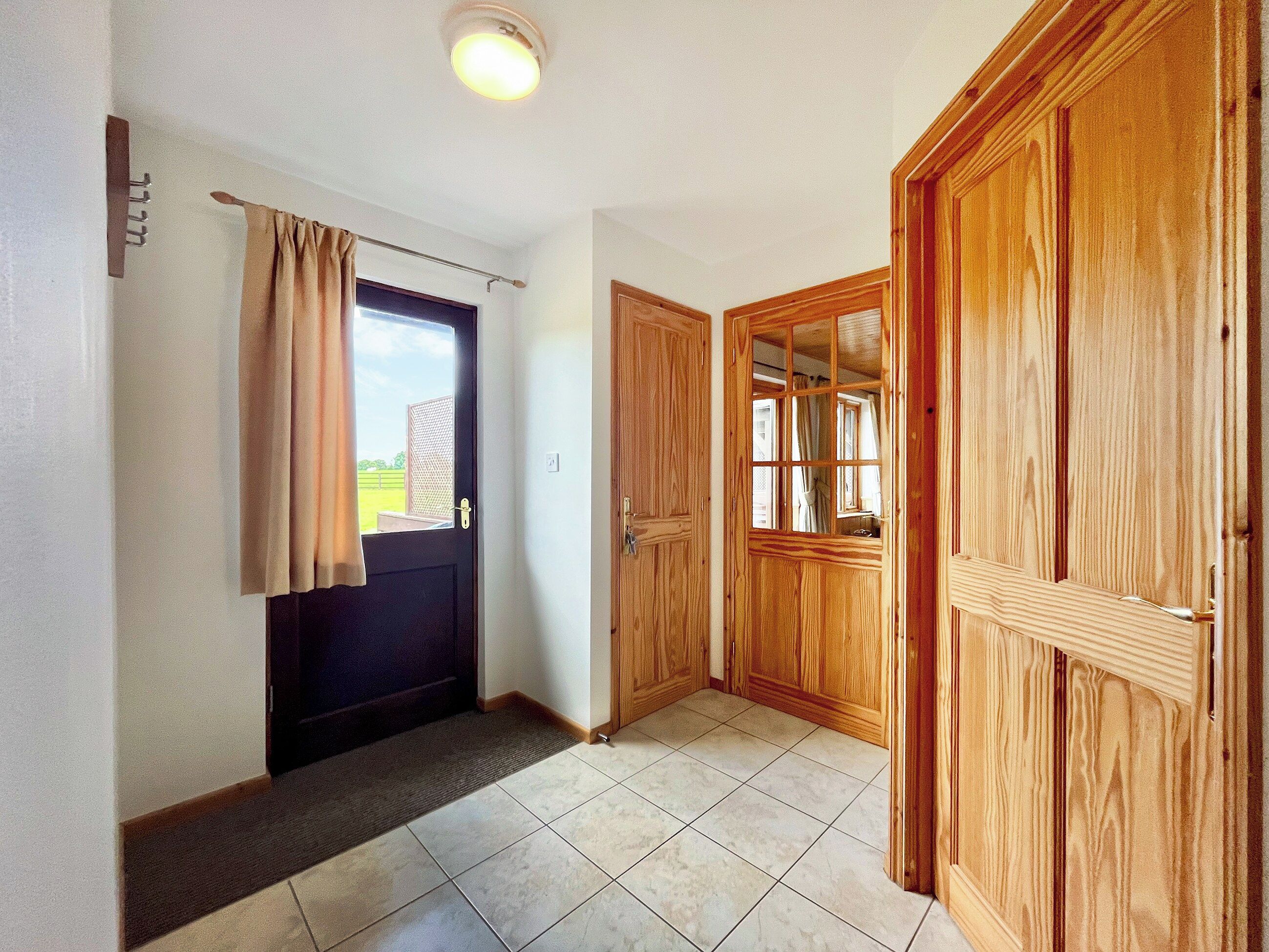 Un pasillo con una puerta, una ventana y un armario de madera.