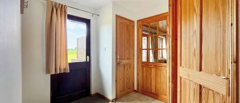 Un pasillo con una puerta, una ventana y un armario de madera.