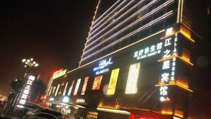 A multi-story building with illuminated signage, including a prominent sign for a hotel and a restaurant. - Anmen Lijiang Inn (Qimen)