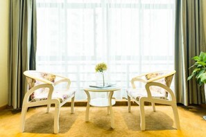 A room with two white chairs, a small round table with a vase, and a large window with curtains. - Anmen Lijiang Inn (Qimen)
