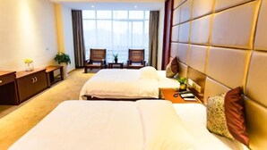 A hotel room with two beds, a desk, a chair, and a view of the city. - Anmen Lijiang Inn (Qimen)