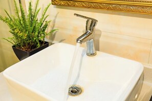 A white bathroom sink with a chrome faucet and a plant in a black pot beside it. - Anmen Lijiang Inn (Qimen)