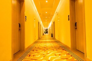 A long, narrow hotel corridor with doors on both sides and a patterned carpet.