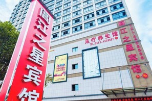 A tall building with a prominent red sign on the left. - Anmen Lijiang Inn (Qimen)