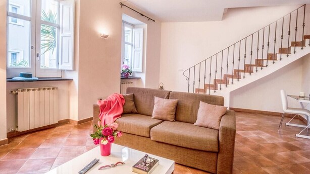 A living room with a sofa, a coffee table, a staircase, and a view of the outside. - Casa Centrale in central Sorrento (Sorrento)