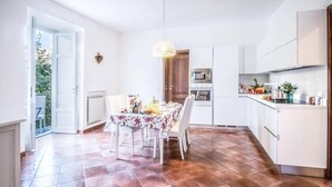 A modern kitchen with white cabinets, a dining table with chairs, and a hanging light fixture. - Casa Centrale in central Sorrento (Sorrento)
