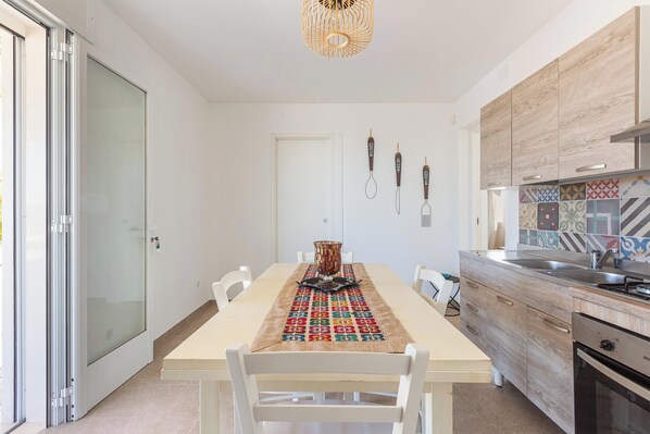A modern kitchen with a dining table, chairs, and a patterned table runner.