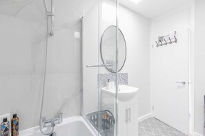 A modern bathroom with a glass shower enclosure, a white sink, and a glass door.