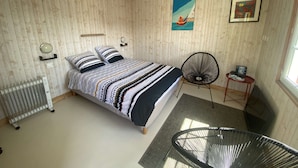 Ein Schlafzimmer mit einem Bett, einem Sessel, einem Heizkörper und Bildern an den Wänden.